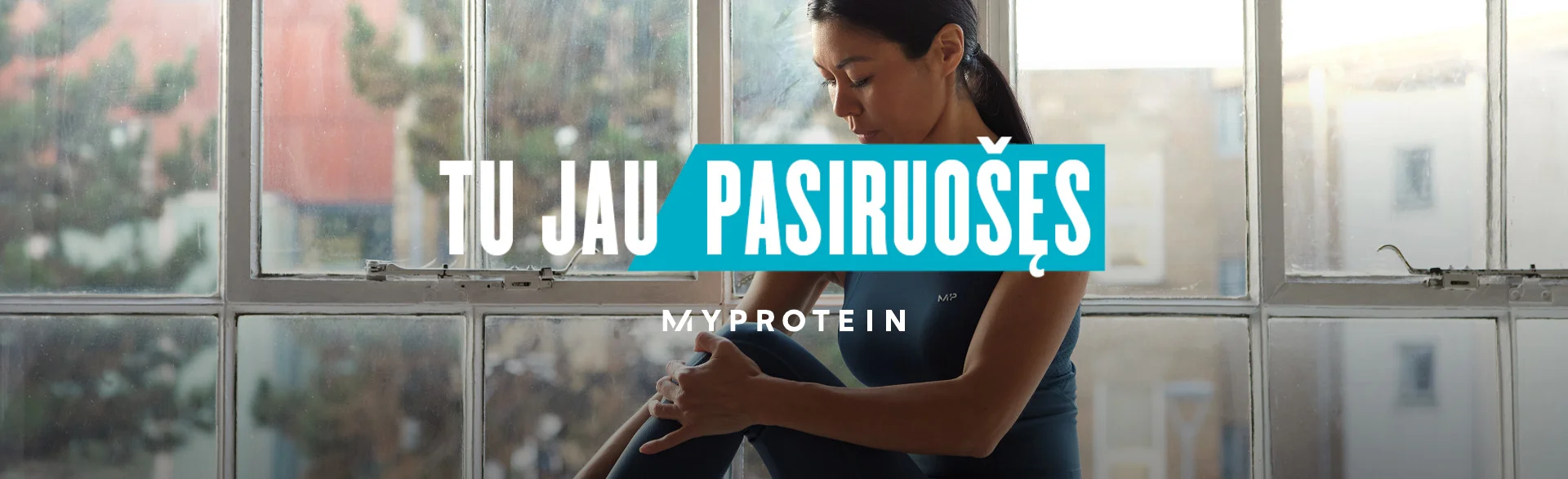 A woman wearing MP gym clothing sat on a window ledge stretching with the text 'You're Already Ready - MYPROTEIN' overlaying the image.