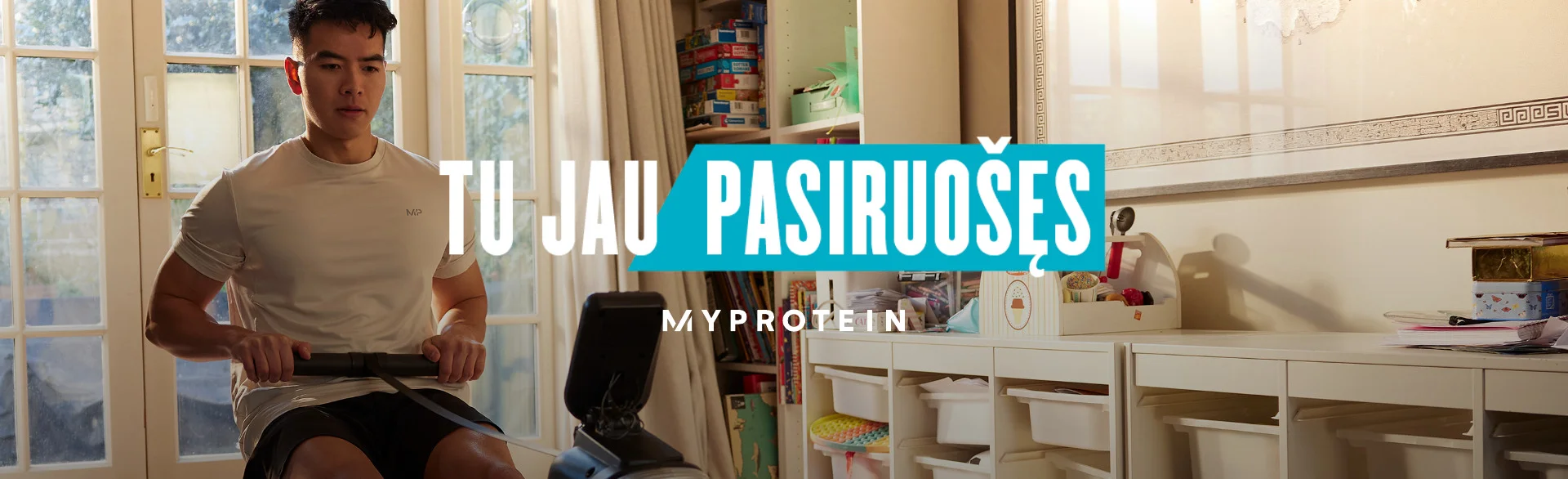 A man workout out on a rowing machine at home with the words 'You're Already Ready - MYPROTEIN' overlaying.